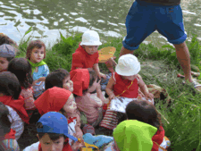 Grup de nens asseguts a la vora mateix del riu.